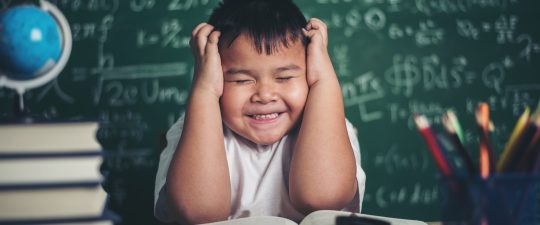 worried boy In classroom with hands on head